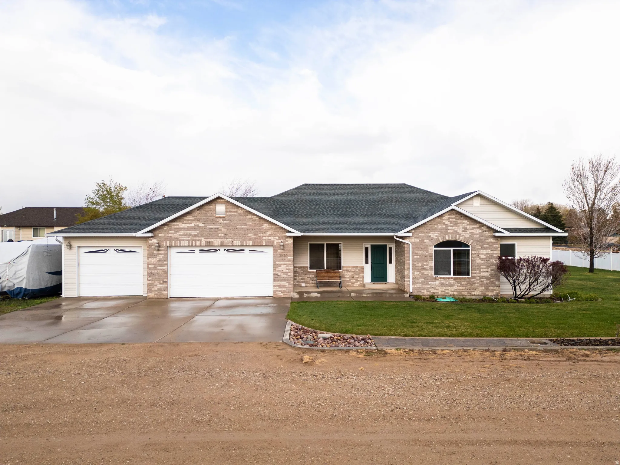 Ranch-style home with a shingled roof, driveway, a porch, an attached garage, and a front lawn