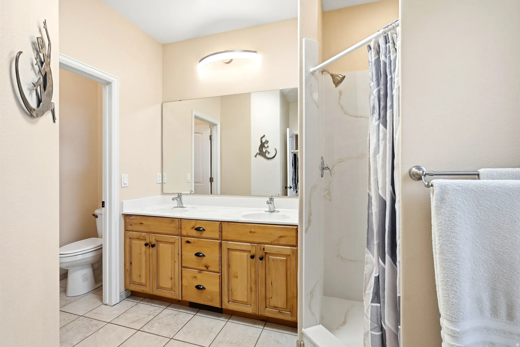 Full bathroom featuring a stall shower, double vanity, and light tile patterned flooring