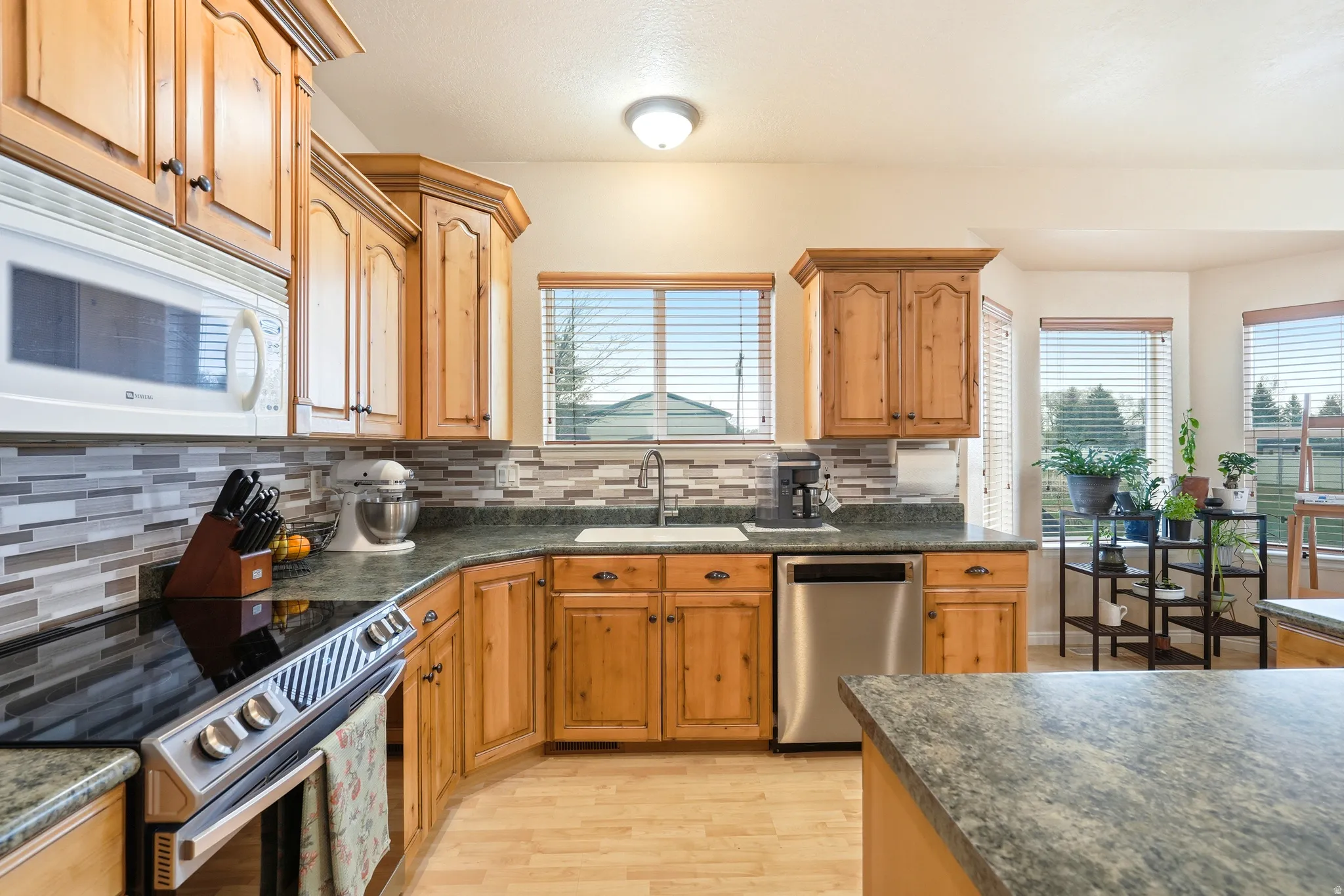Kitchen with stainless steel appliances, light wood finished floors, plenty of natural light, and backsplash
