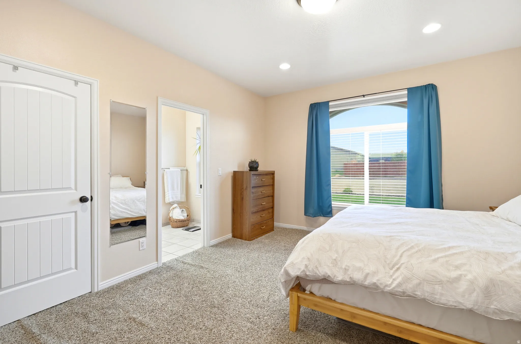 Bedroom with ensuite bathroom, recessed lighting, and light colored carpet