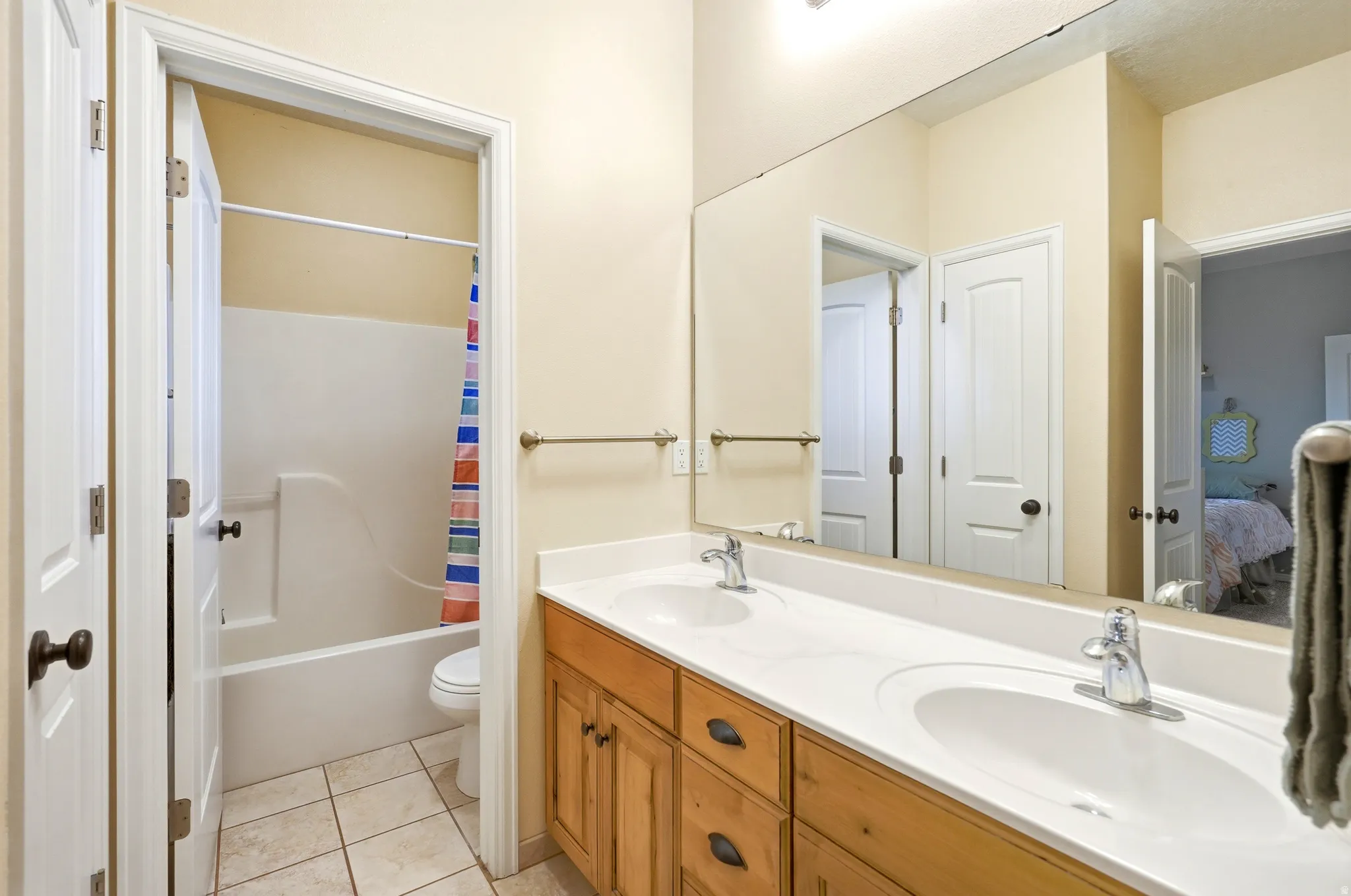 Full bath featuring double vanity, ensuite bath, light tile patterned floors, and shower / bath combo with shower curtain