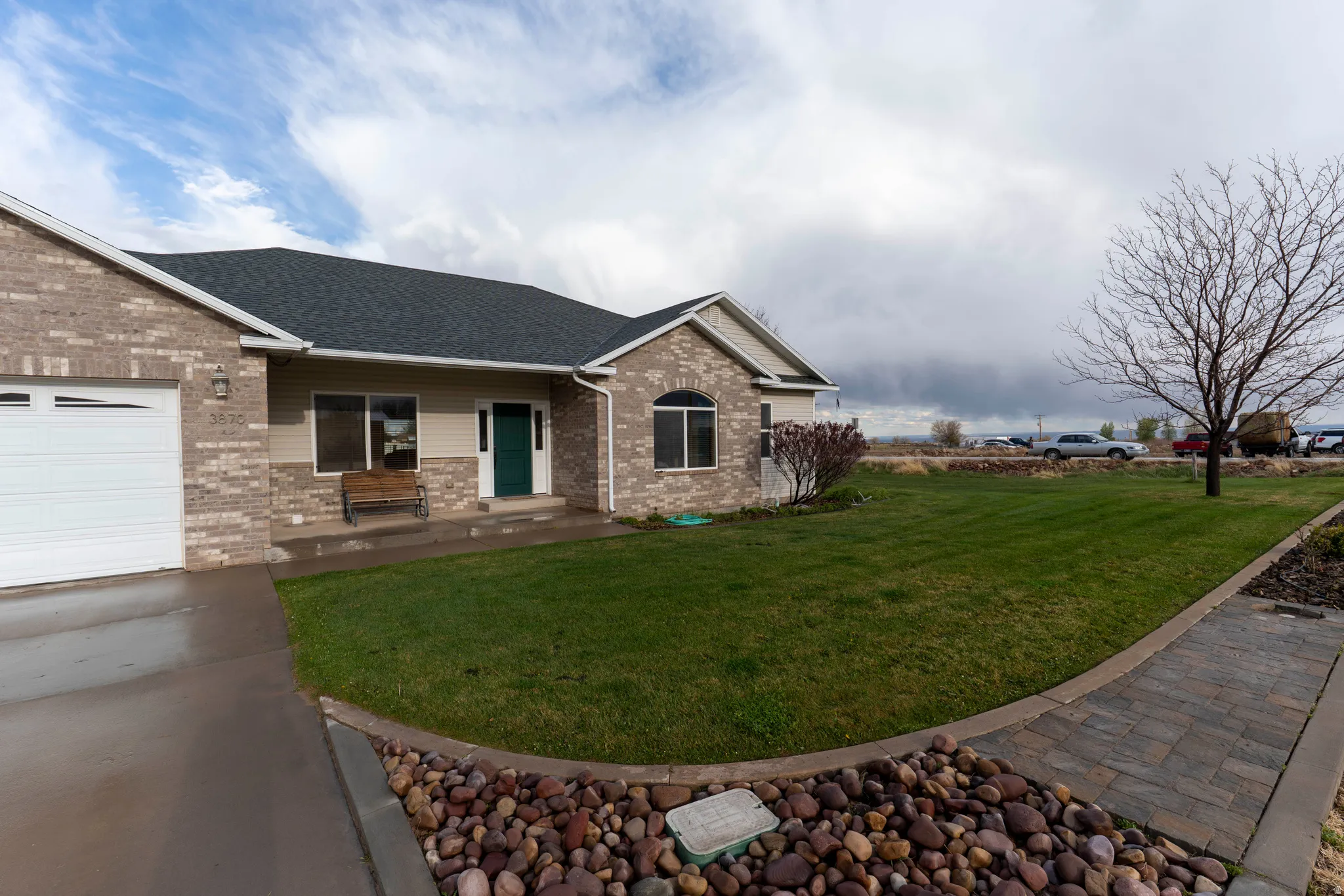Ranch-style home featuring brick siding, a front lawn, a porch, roof with shingles, and an attached garage
