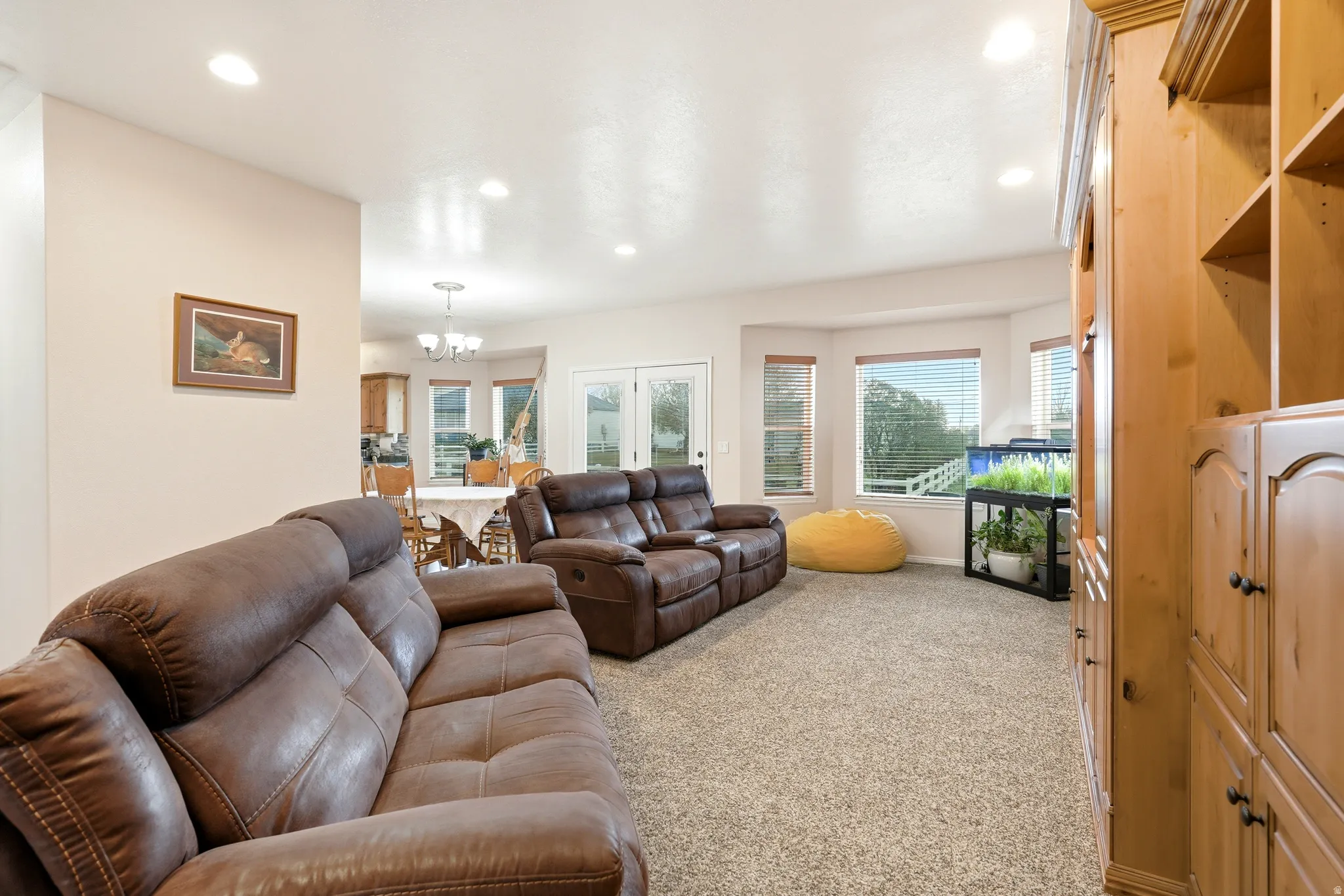 Living area with suspended lighting, light colored carpet, and french doors