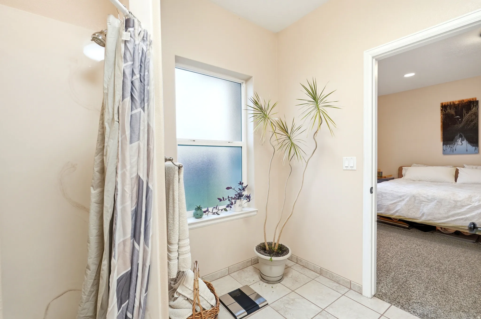 Bathroom featuring light colored carpet, a shower with curtain, light tile patterned floors, and ensuite bathroom