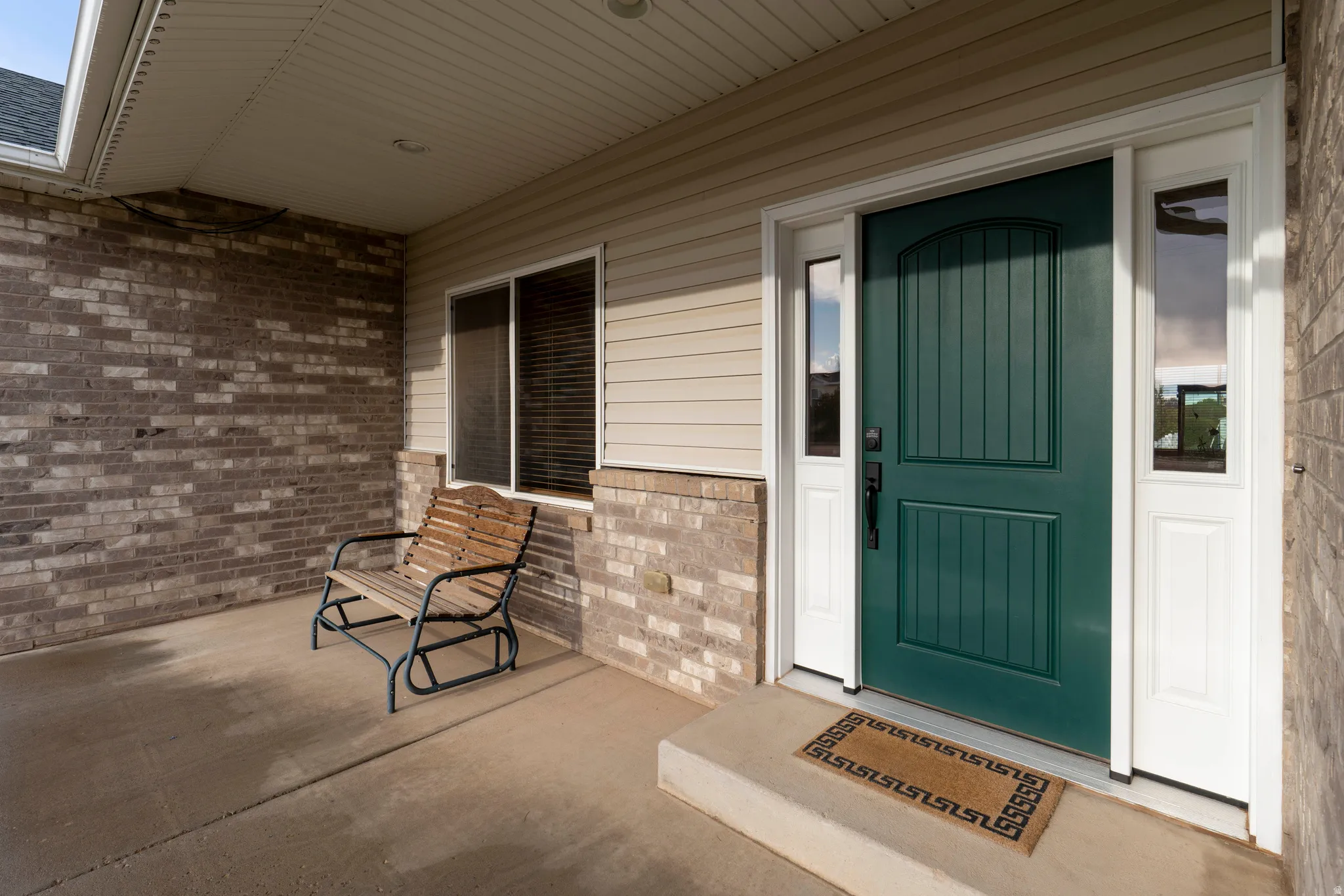 Doorway to property featuring brick siding and covered porch