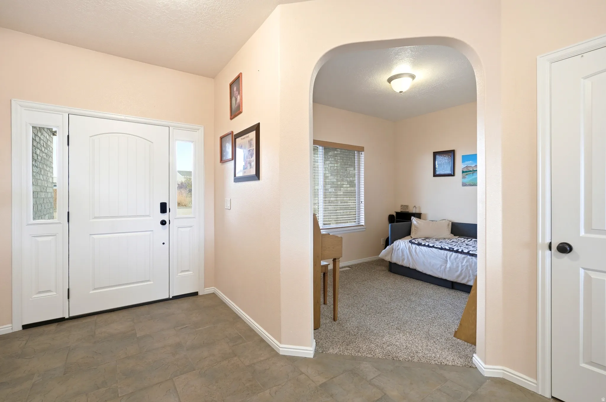 Entryway with arched walkways, stone finish flooring, a textured ceiling, and carpet floors