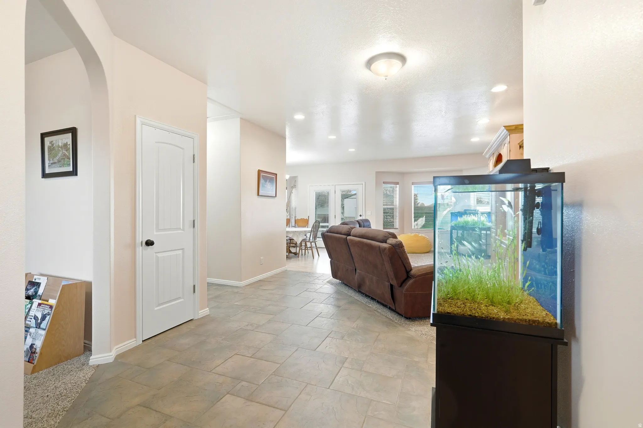 Living area with stone finish flooring, arched walkways, and recessed lighting