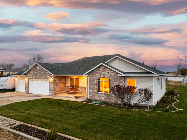 Ranch-style house featuring an attached garage, concrete driveway, roof with shingles, and a lawn