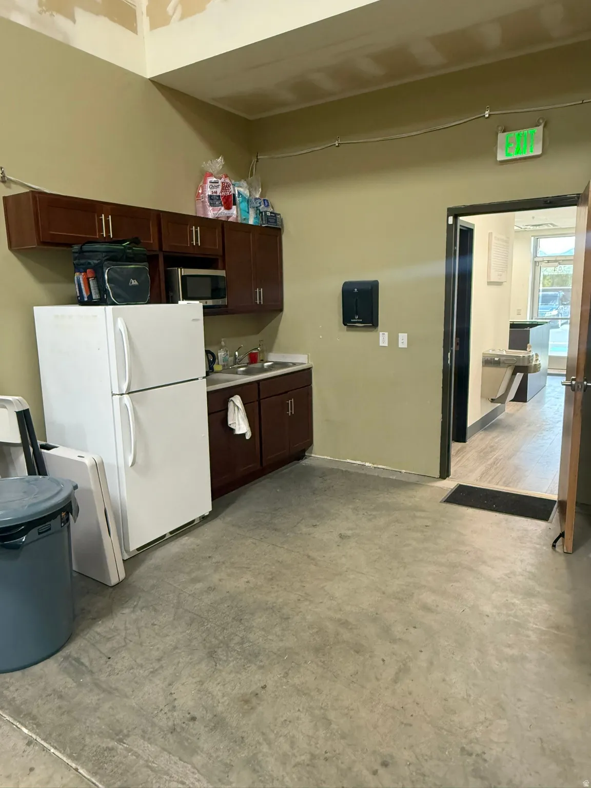 Kitchen featuring freestanding refrigerator, light countertops, dark wood finish cabinets, and stainless steel microwave