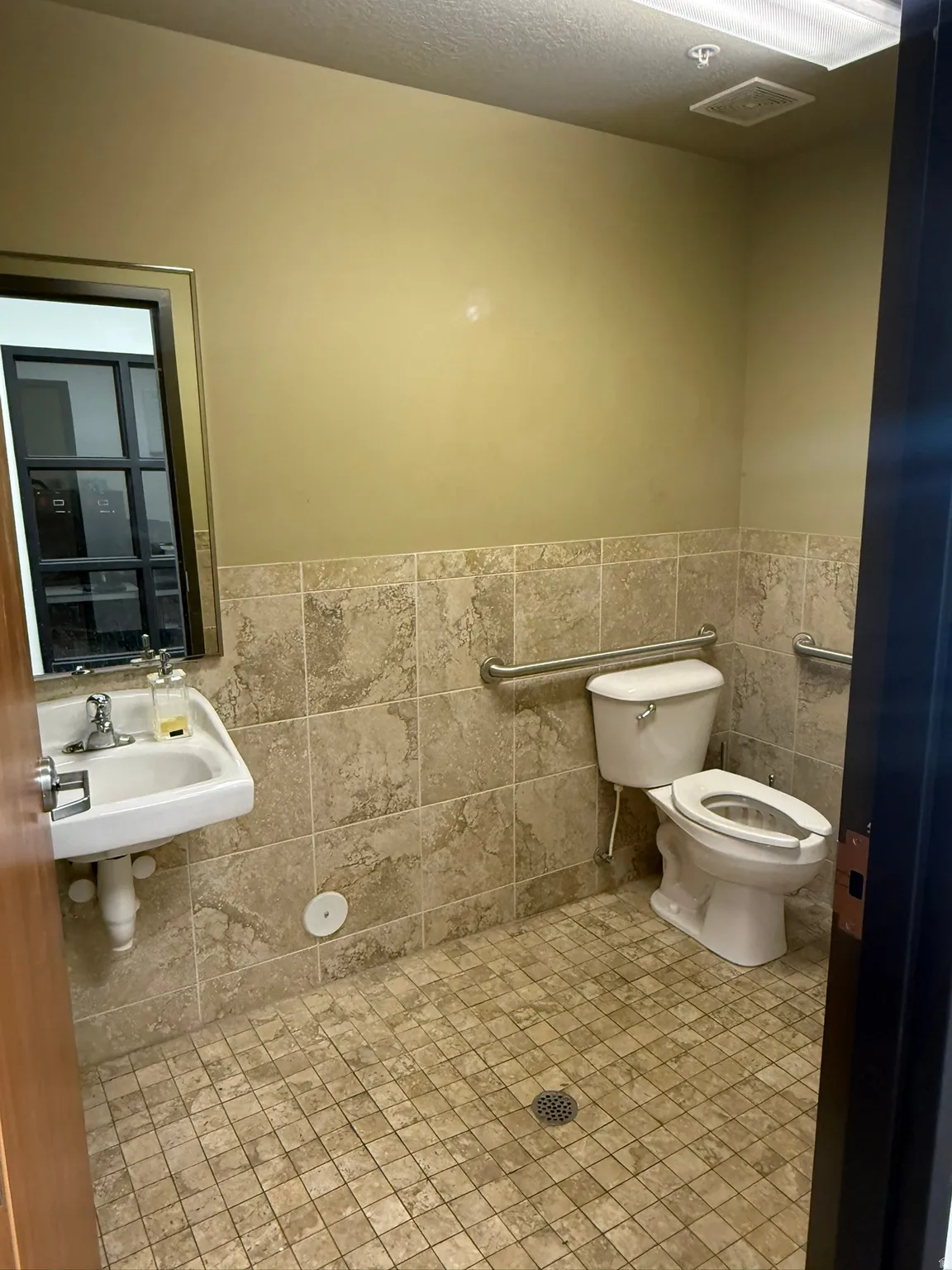 Bathroom with tile walls, wainscoting, tile patterned flooring, and a textured ceiling