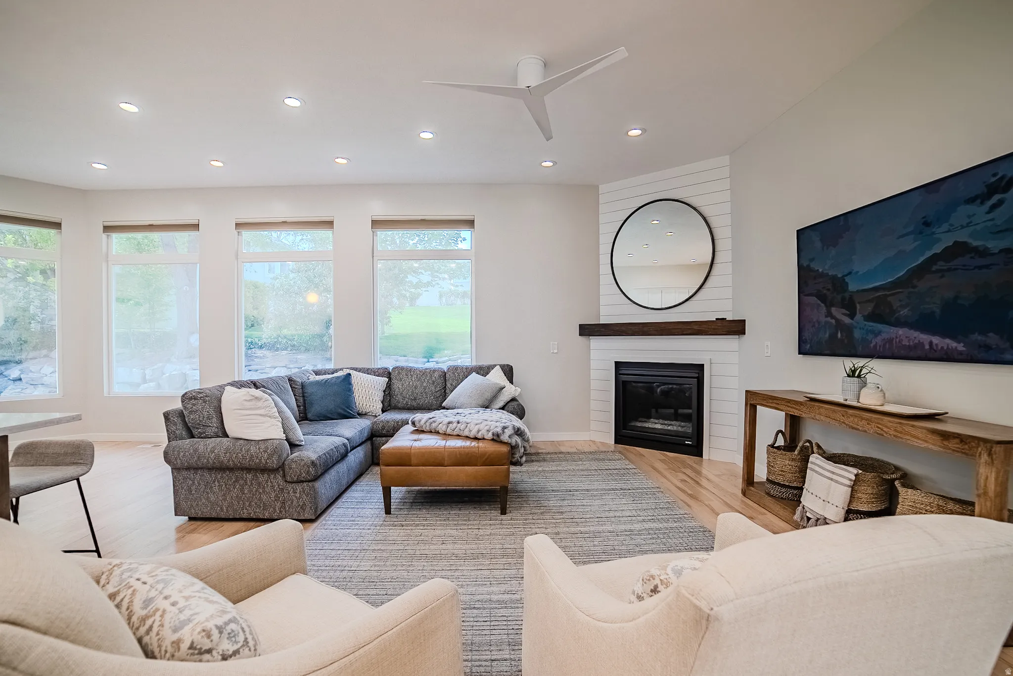 Living room featuring a large fireplace, light wood-type flooring, a ceiling fan, and recessed lighting