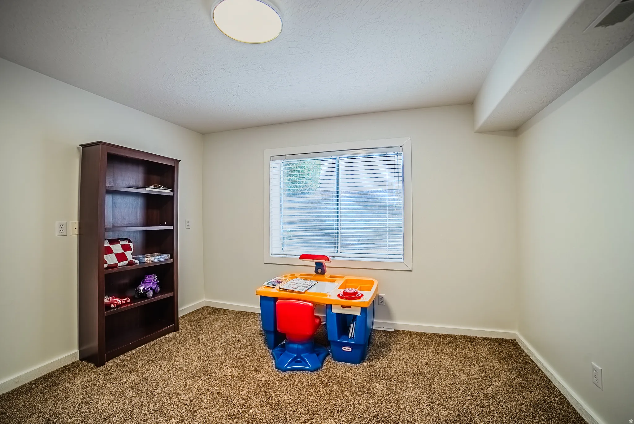 Playroom with dark colored carpet and a textured ceiling
