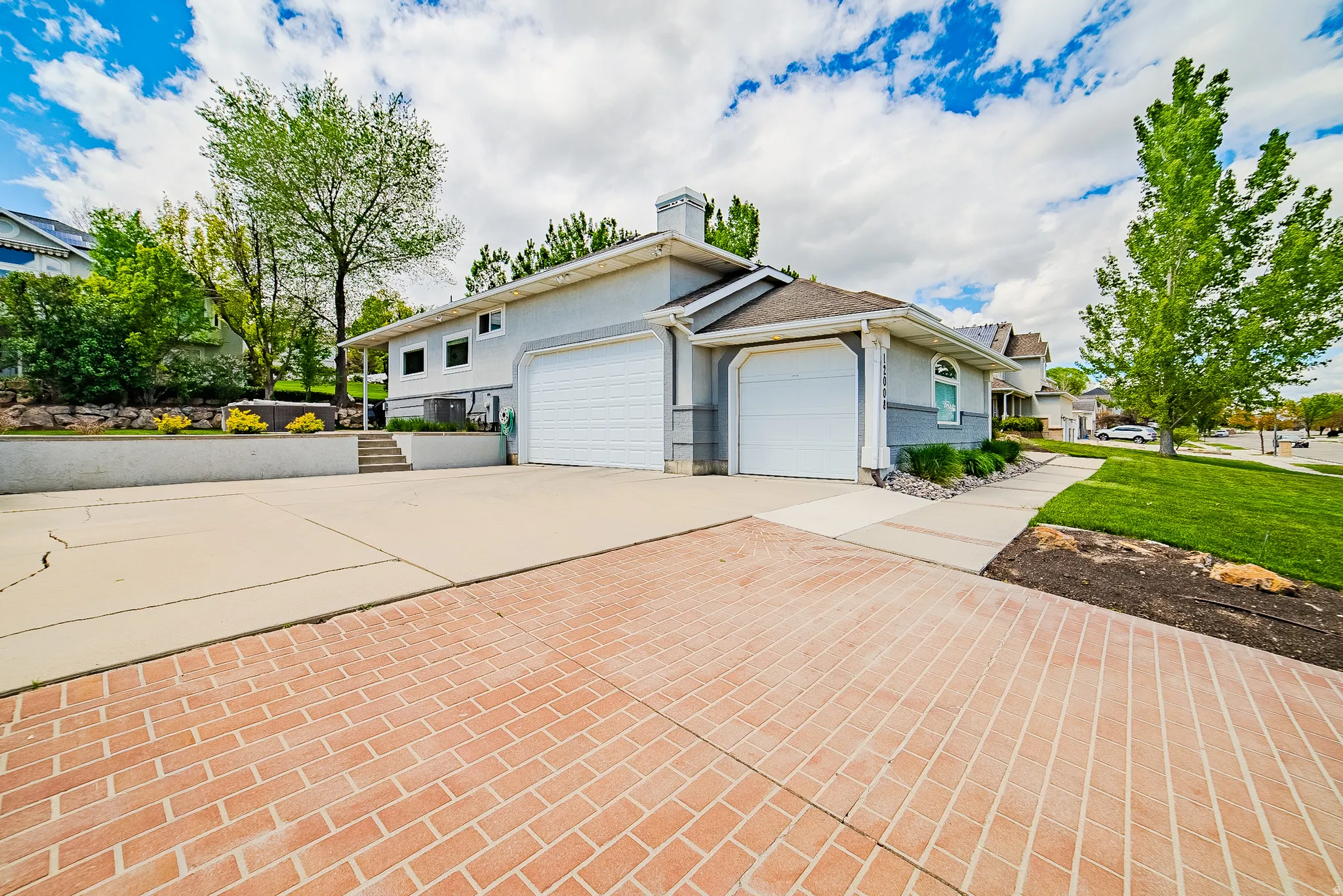 View of front of property featuring an attached garage, driveway, stucco siding, and a chimney