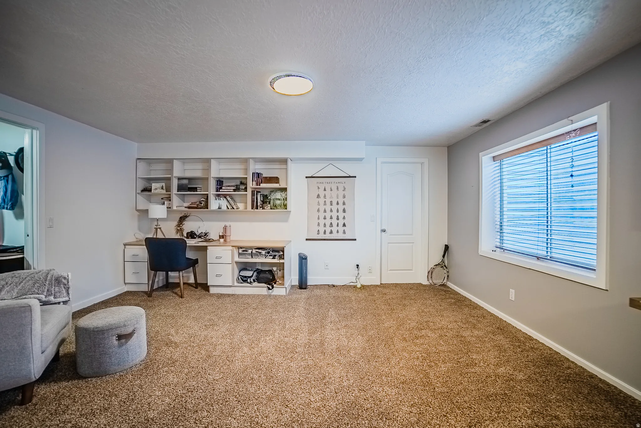 Carpeted home office with a textured ceiling and built in study area