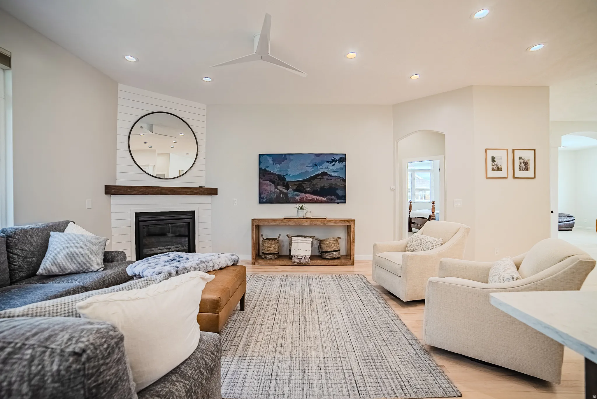 Living area with a fireplace, arched walkways, recessed lighting, and light wood-style floors