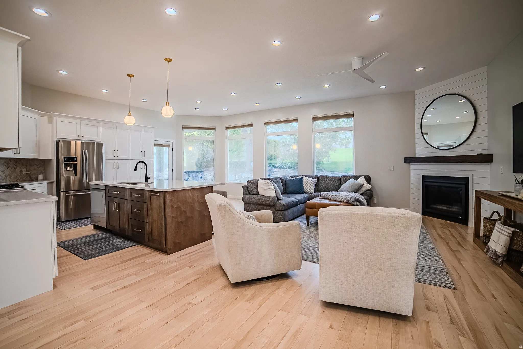 Living room with a large fireplace, light wood finished floors, and recessed lighting
