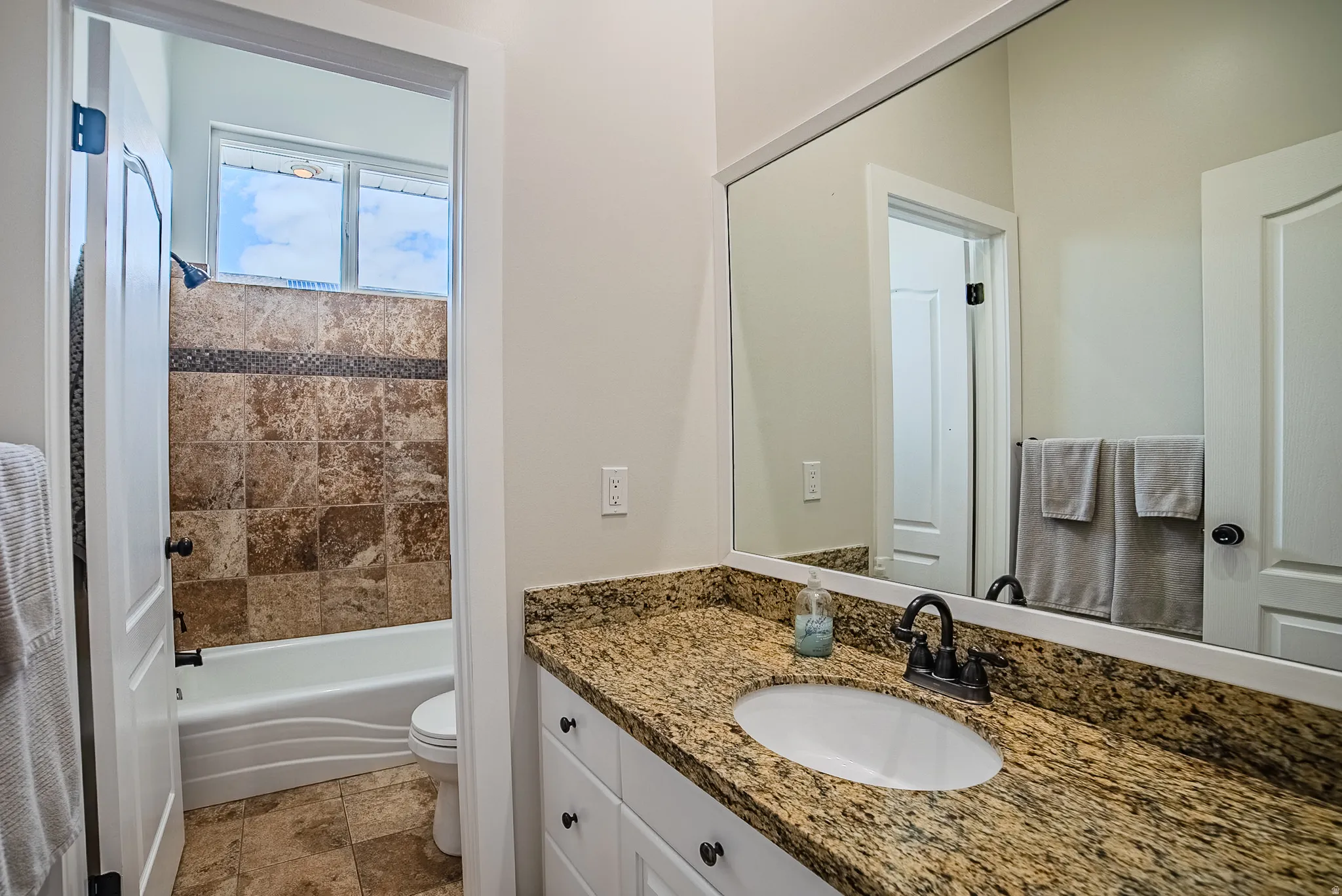 Full bathroom with vanity, light stone finish floors, and shower / washtub combination
