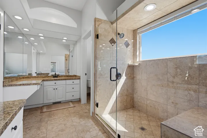 Glass-enclosed shower with a built-in bench, tiled walls, and a window