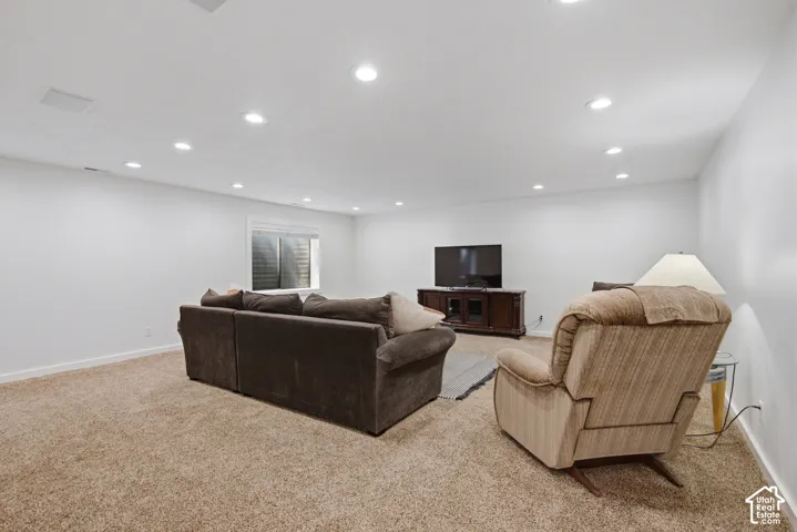 Recessed lighting, light-colored carpeting, and a window with a white frame