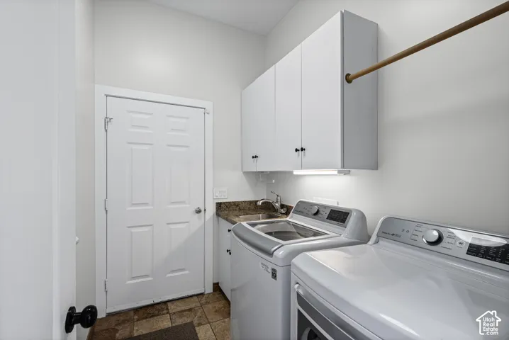 Laundry area featuring white cabinetry, integrated sink, and granite-style countertop