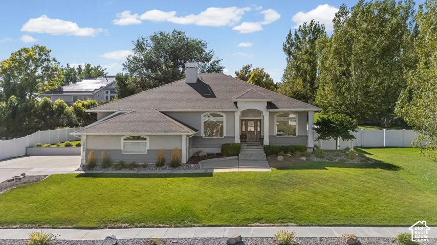 Gray exterior with stone accents, a dark shingle roof, arched transom windows, and a concrete pathway