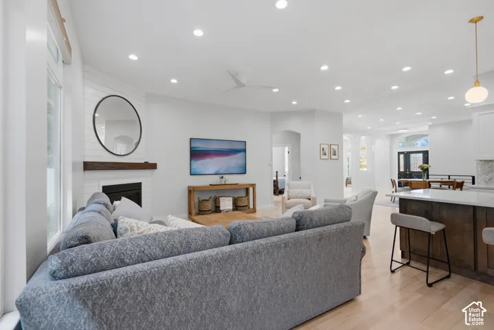 Hardwood flooring, recessed lighting, and a fireplace with a wood mantel