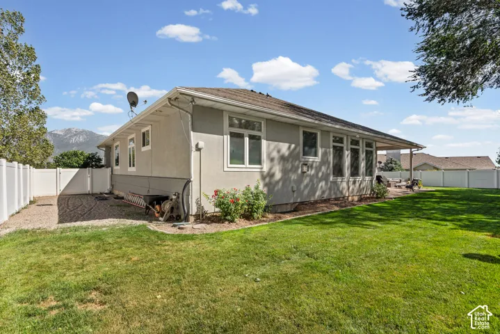 Manicured lawn with a stucco exterior, multiple windows, and covered patio space