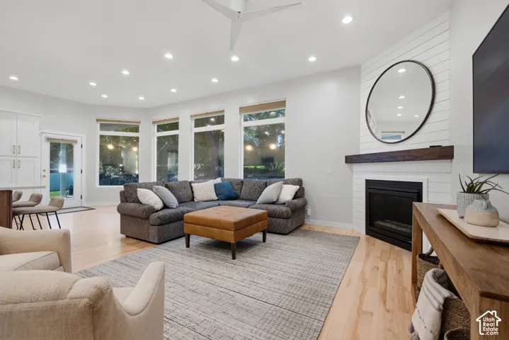 Recessed lighting, light wood-finish flooring, multiple windows, built-in fireplace with wood mantel, and shiplap accent wall