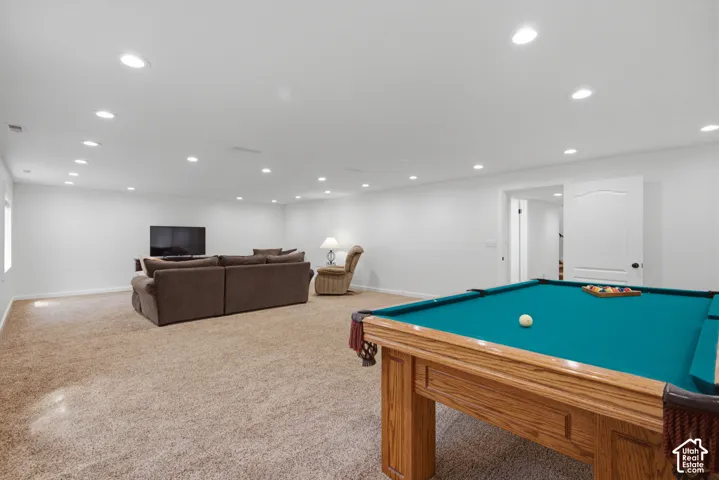 Recessed lighting illuminates the expansive carpeted room with a white door featuring a decorative arch panel