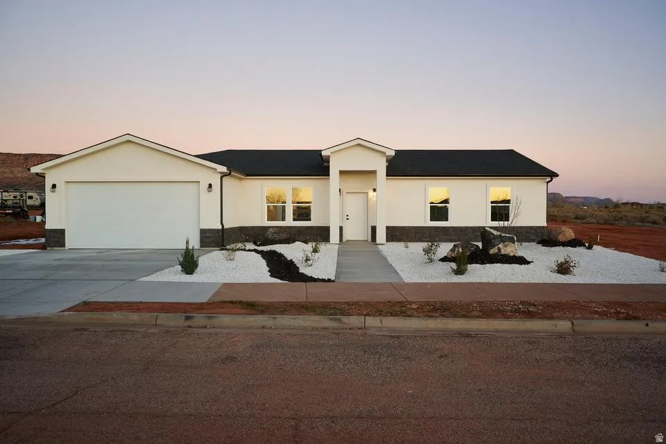 Ranch-style house featuring stucco siding, concrete driveway, a garage, and stone siding