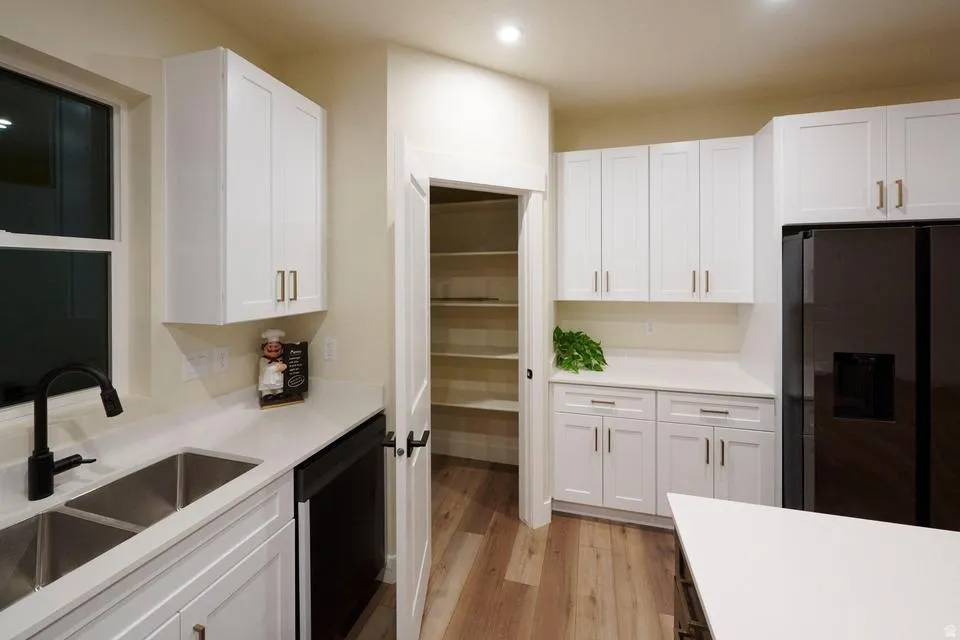 Kitchen with white cabinetry, fridge with ice dispenser, and recessed lighting