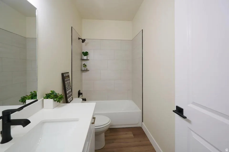 Bathroom with vanity, dark wood-style floors, and bathtub / shower combination