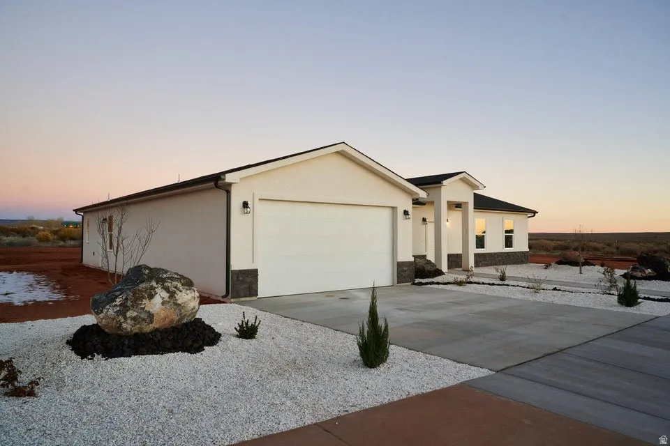 View of front of house featuring driveway, stucco siding, and stone siding