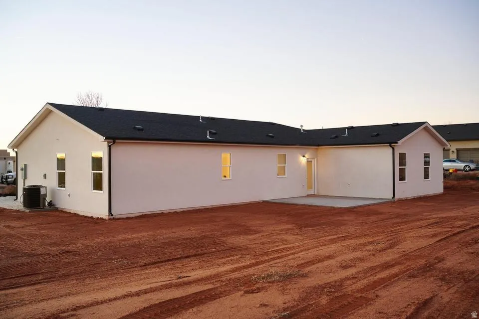 Back of property at dusk featuring stucco siding and a patio area