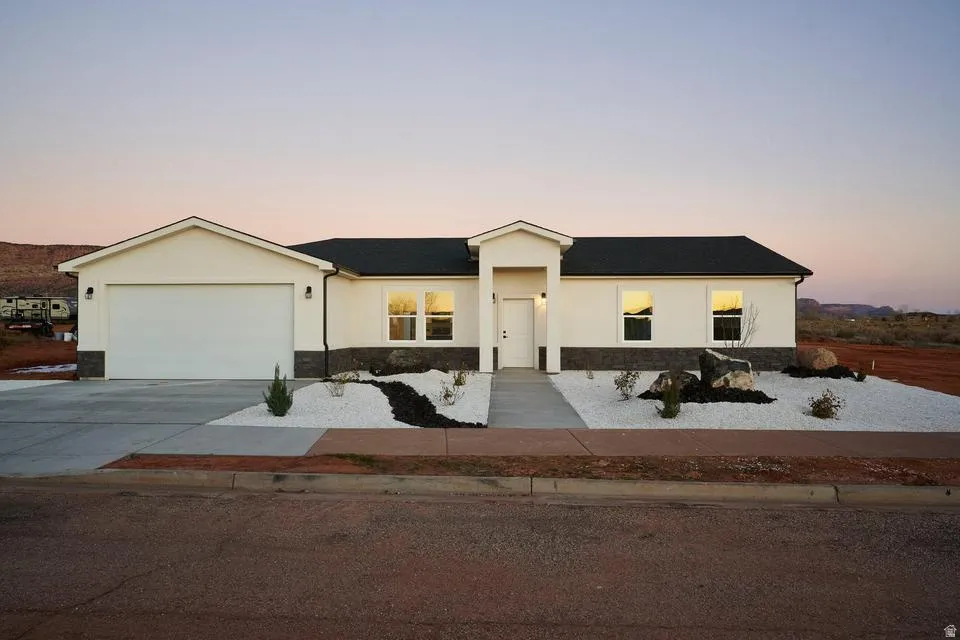 View of front facade featuring driveway, stucco siding, and an attached garage