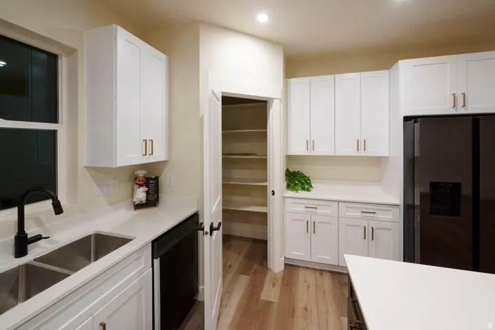 Kitchen with white cabinetry, fridge with ice dispenser, and recessed lighting