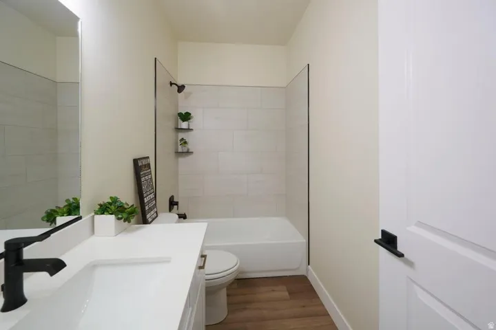 Bathroom with vanity, dark wood-style floors, and bathtub / shower combination