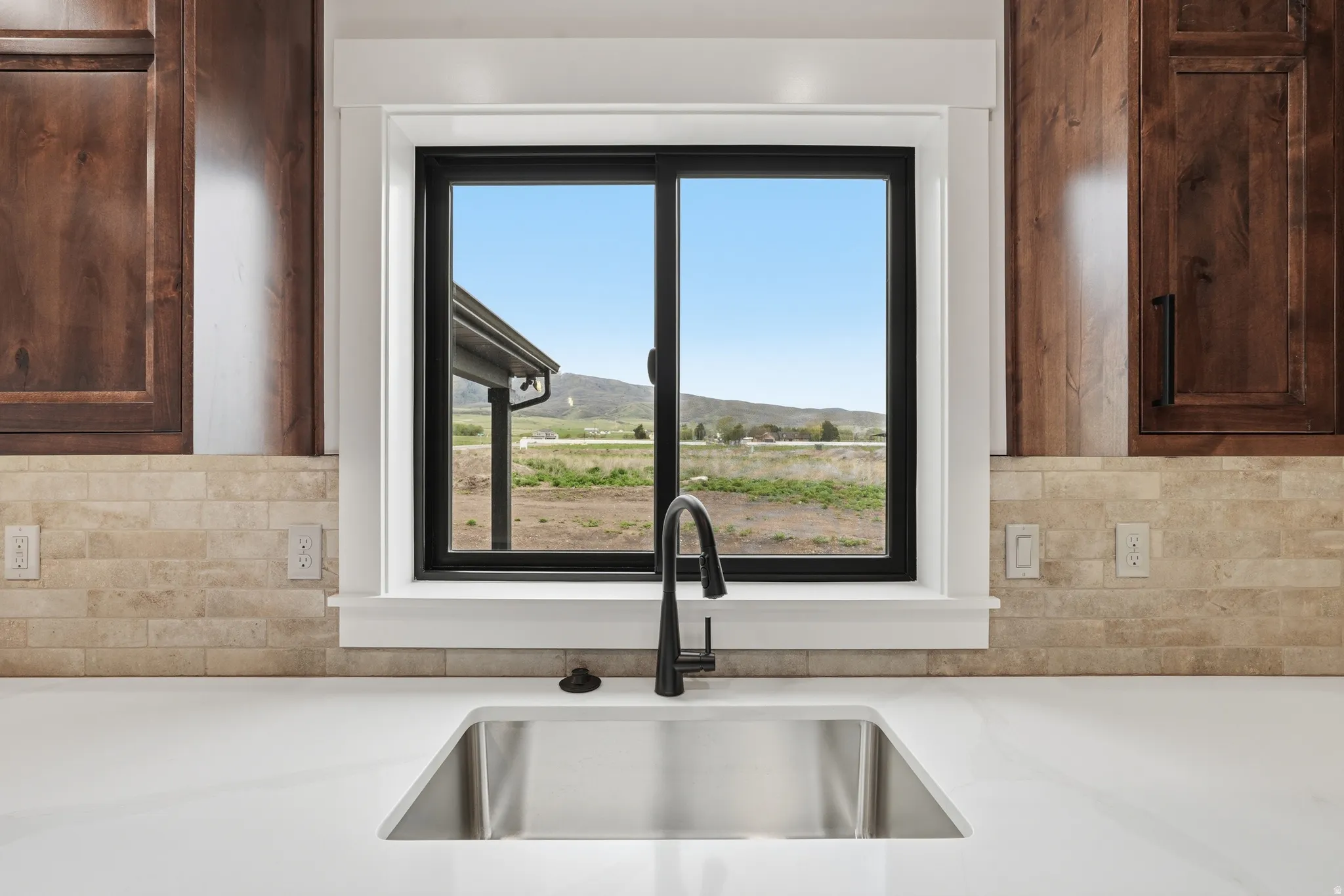 Kitchen view of backsplash, dark wood finish cabinets, and light stone countertops
