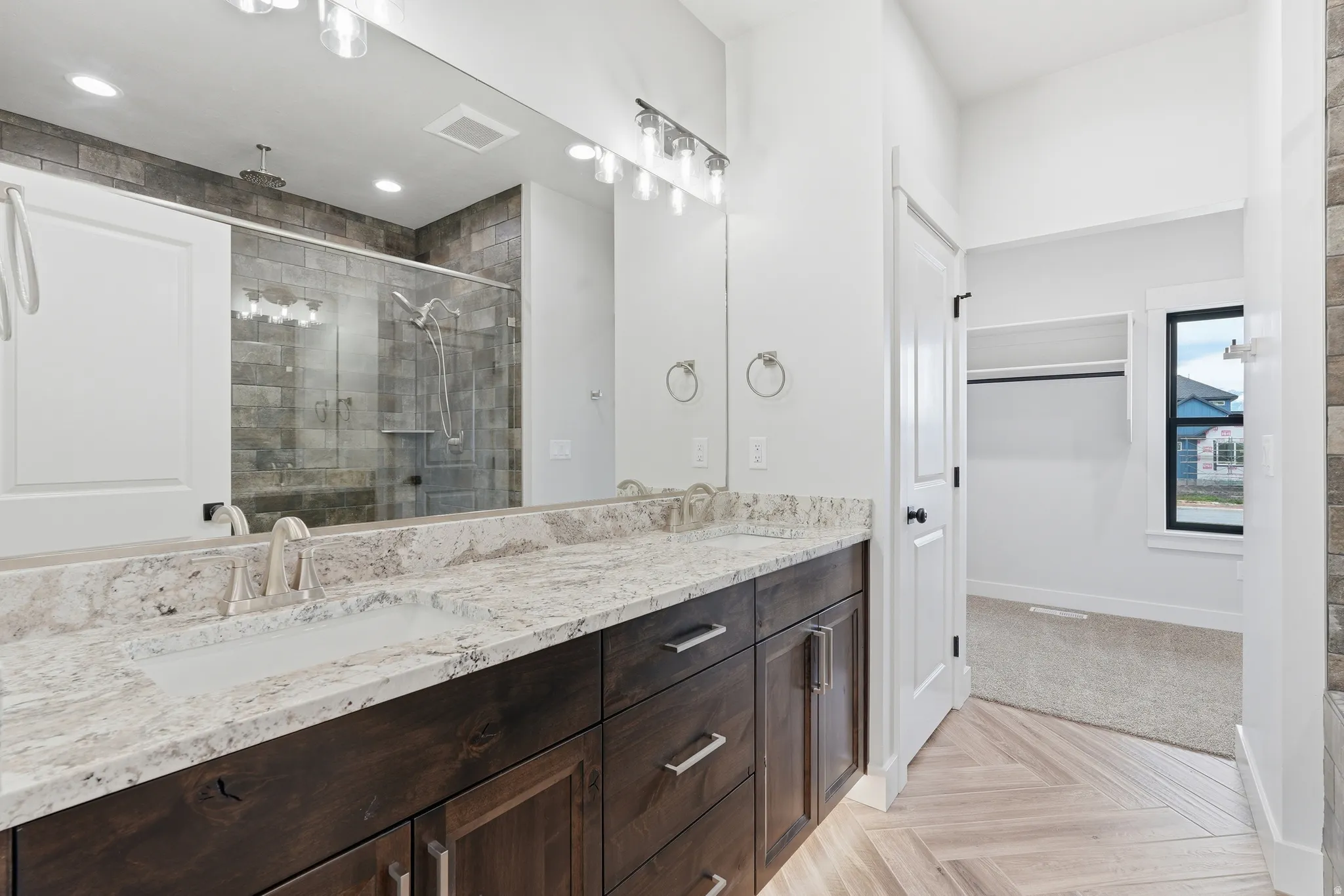 Bathroom with double vanity, parquet floors, a shower stall, and a spacious closet