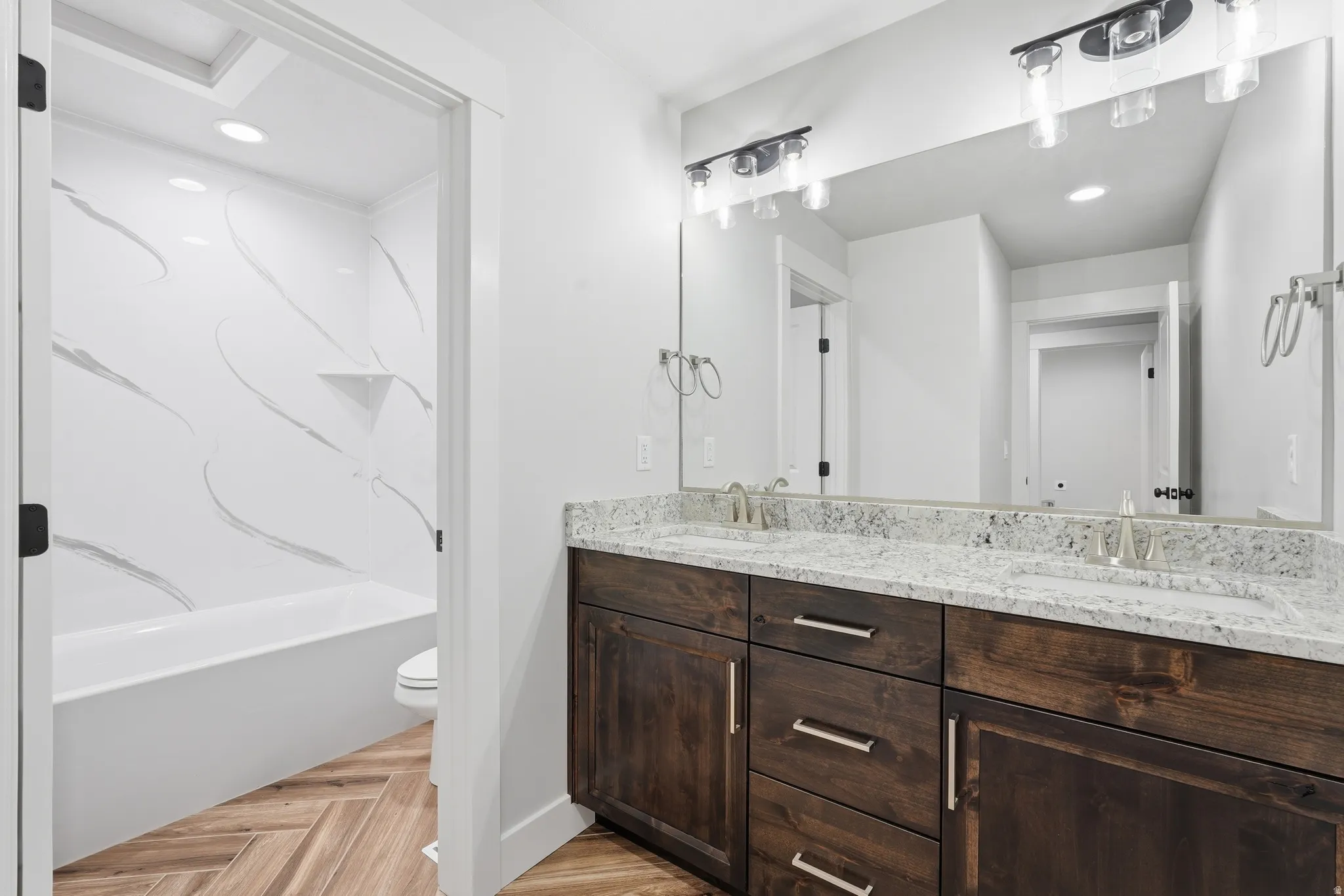 Bathroom featuring double vanity, recessed lighting, parquet floors, and shower / bath combination