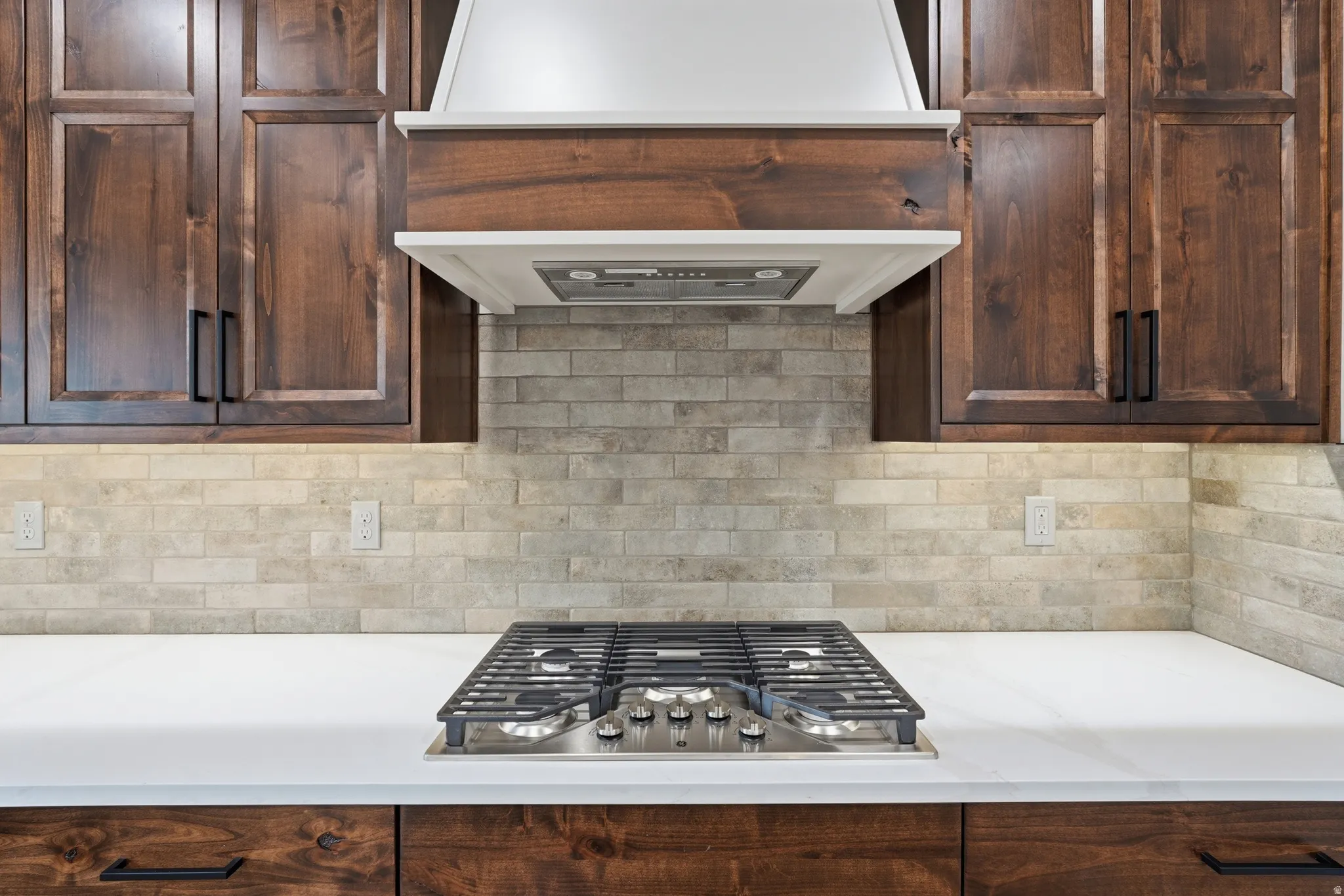 Kitchen featuring backsplash, stainless steel gas stovetop, and dark wood finish cabinets