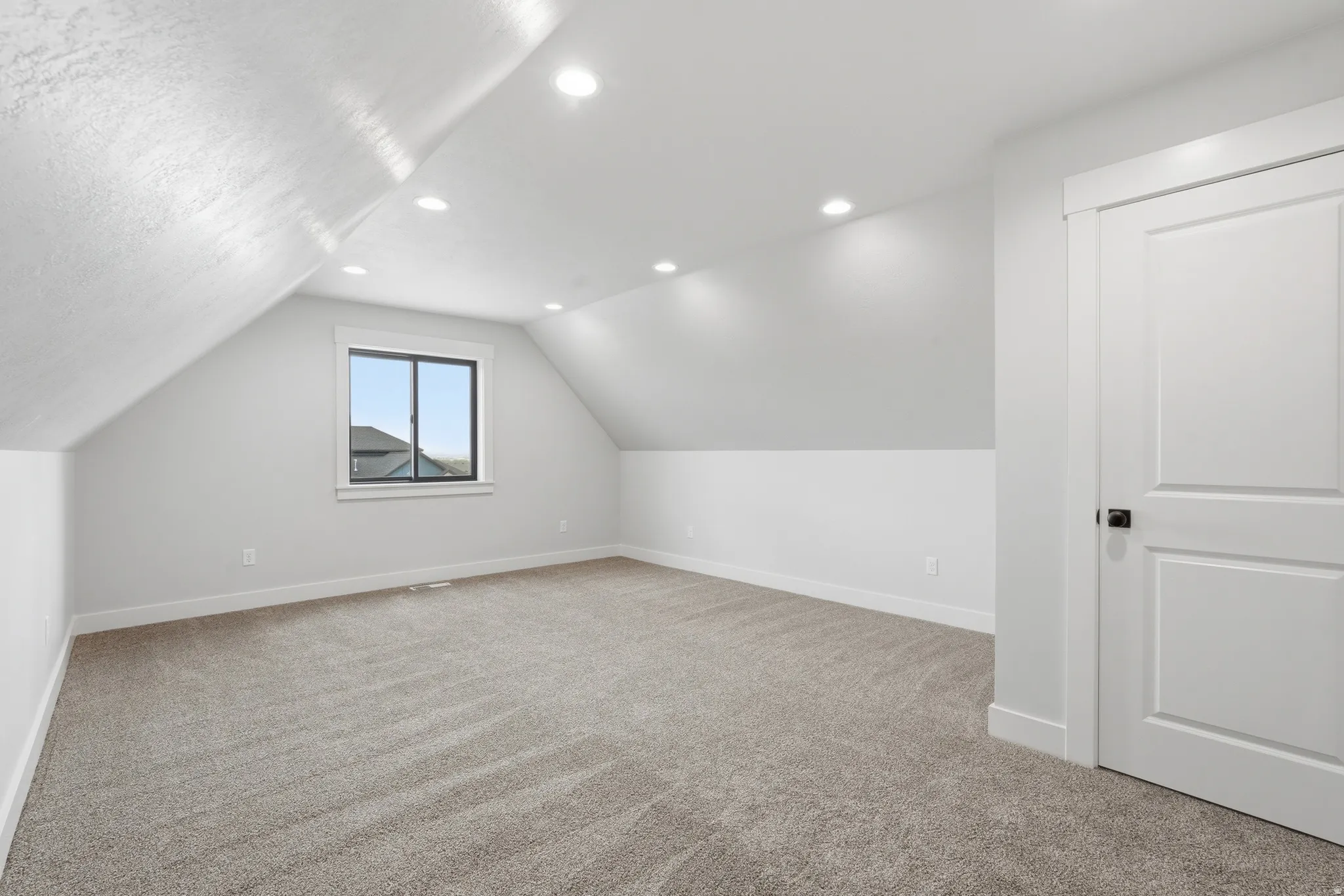 Additional living space with light carpet and recessed lighting