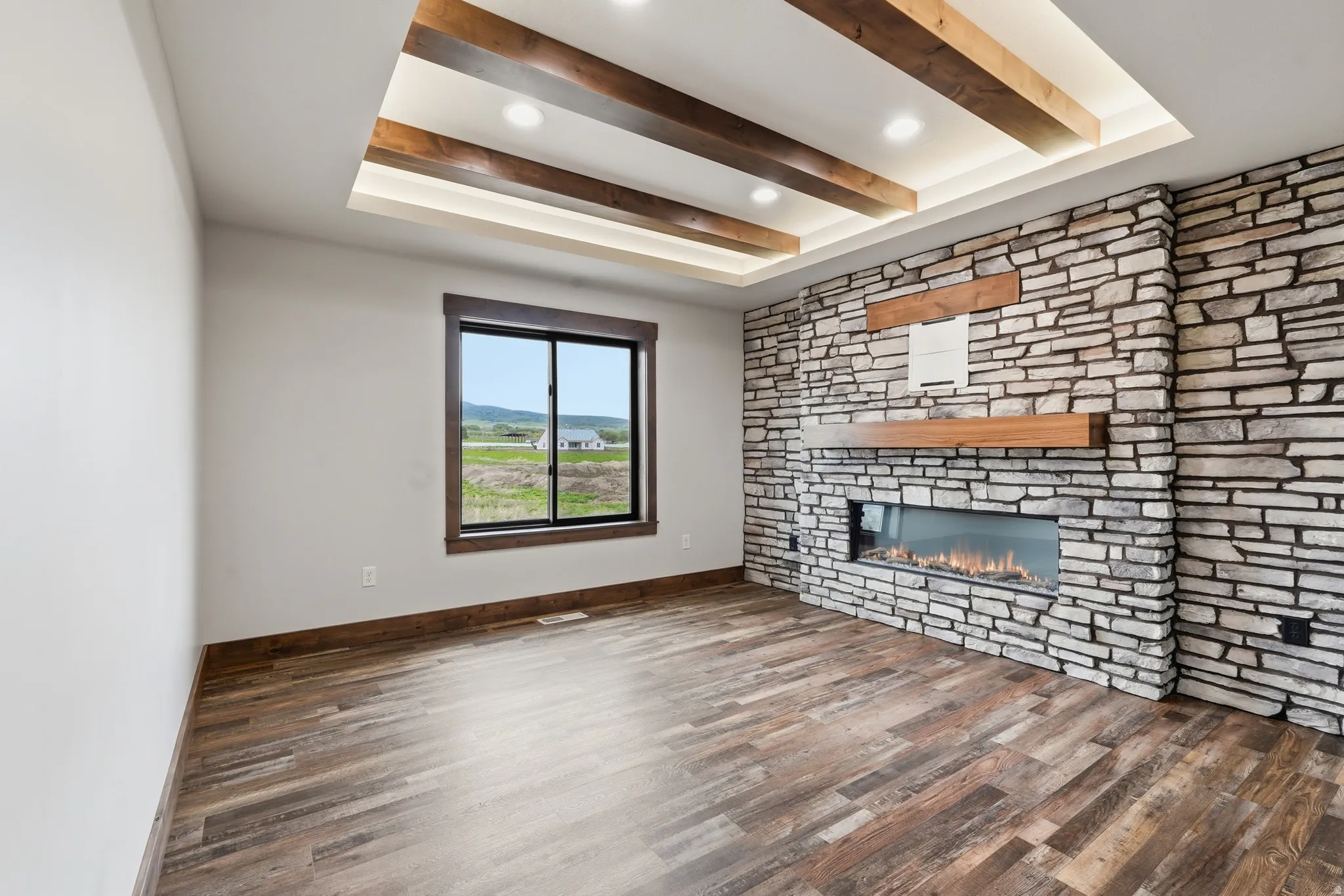 Unfurnished living room with a tray ceiling, dark wood-type flooring, a fireplace, and recessed lighting