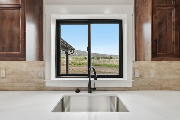 Kitchen view of backsplash, dark wood finish cabinets, and light stone countertops