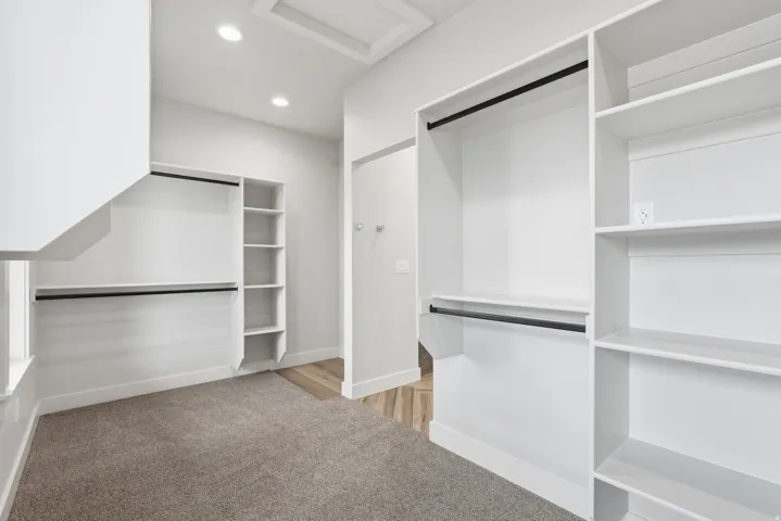 Walk in closet with attic access and light colored carpet