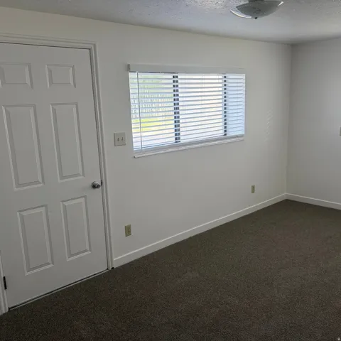 Spare room featuring dark colored carpet and a textured ceiling