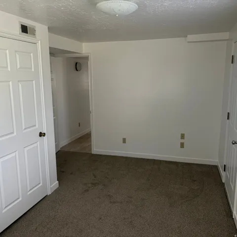 Unfurnished bedroom featuring dark carpet and a textured ceiling