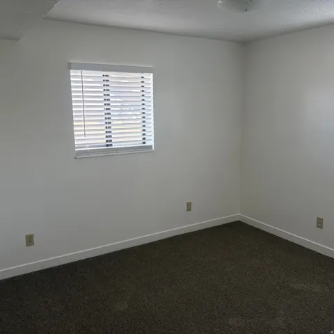 Empty room featuring dark carpet and a textured ceiling