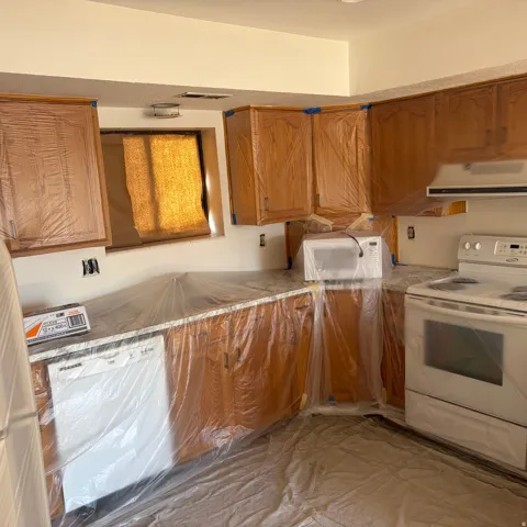 Kitchen featuring white appliances, wood finish cabinets, range hood, and light countertops