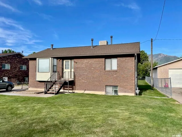Back of house with brick siding, a chimney, and a mountain view